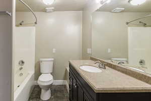 Full bathroom featuring tile patterned floors, vanity, toilet, and shower / washtub combination