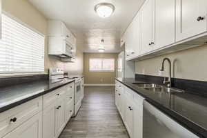 Kitchen featuring white appliances, dark hardwood / wood-style floors, white cabinetry, and sink