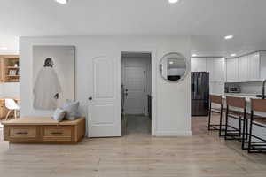 Interior space with stainless steel fridge with ice dispenser, a textured ceiling, light hardwood / wood-style flooring, and white cabinetry