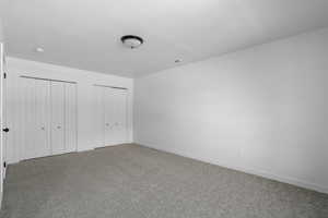 Unfurnished bedroom featuring carpet flooring and two closets