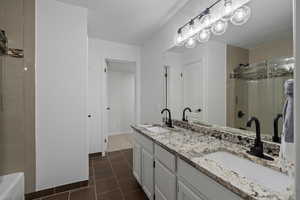 Bathroom featuring tile patterned floors, vanity, and a tile shower