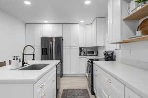 Kitchen featuring stainless steel appliances, white cabinetry, light hardwood / wood-style floors, and sink