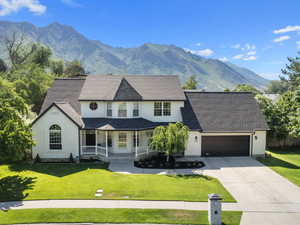 View of front of property featuring a mountain view, a porch, a garage, and a front lawn