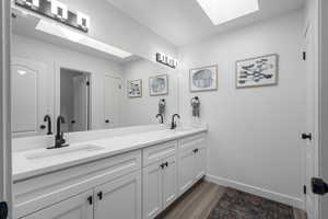 Bathroom with a skylight, vanity, and wood-type flooring