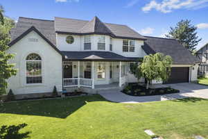 Victorian house with a garage, covered porch, and a front yard