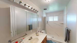 Bathroom with vanity, a textured ceiling, toilet, and walk in shower