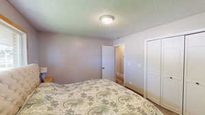 Carpeted bedroom featuring a textured ceiling and a closet