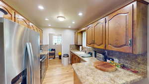 Kitchen with light hardwood / wood-style floors, sink, backsplash, and appliances with stainless steel finishes