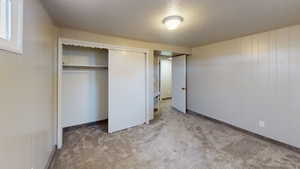 Unfurnished bedroom featuring a closet, light colored carpet, and a textured ceiling