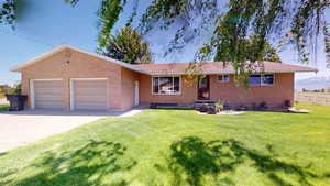 Single story home featuring a garage and a front lawn