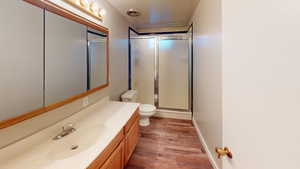 Bathroom featuring wood-type flooring, vanity, toilet, and an enclosed shower