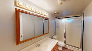 Bathroom featuring vanity, toilet, and a shower with shower door