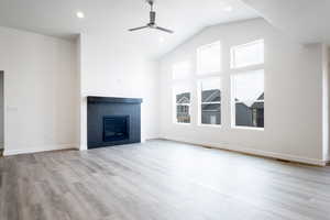 Unfurnished living room featuring ceiling fan, vaulted ceiling, and light wood-type flooring