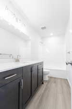 Full bathroom with vanity, wood-type flooring, tub / shower combination, and toilet