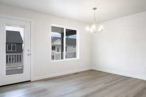 Unfurnished dining area featuring an inviting chandelier and light hardwood / wood-style flooring