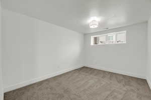 Carpeted spare room with a textured ceiling