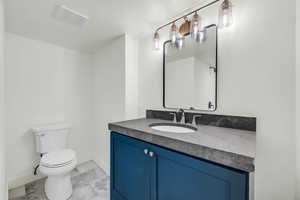 Bathroom featuring vanity, a textured ceiling, and toilet