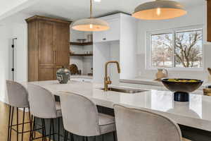 Kitchen featuring pendant lighting, white cabinetry, sink, and a breakfast bar area