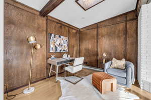 Home office with baseboard heating, wooden walls, hardwood / wood-style floors, and beamed ceiling