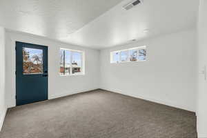 Carpeted spare room featuring a textured ceiling