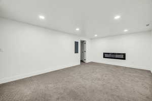 Unfurnished living room featuring carpet and electric panel