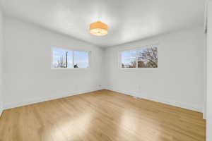 Spare room featuring light wood-type flooring and vaulted ceiling