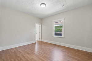 Spare room featuring a textured ceiling and light hardwood / wood-style flooring