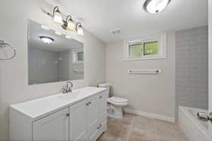 Full bathroom featuring tile patterned floors, vanity, a textured ceiling, toilet, and tiled shower / bath