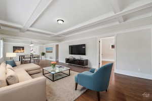 Living room with beam ceiling, ornamental molding, and wood-type flooring