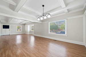 Unfurnished room featuring beamed ceiling, wood-type flooring, coffered ceiling, and ornamental molding