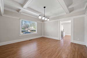 Unfurnished dining area featuring beam ceiling, crown molding, coffered ceiling, and hardwood / wood-style flooring