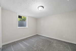 Carpeted spare room featuring a textured ceiling