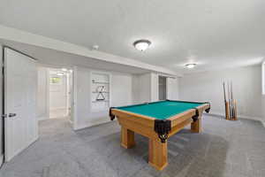 Recreation room featuring built in shelves, a textured ceiling, carpet floors, and billiards