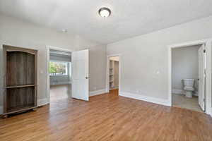 Unfurnished bedroom featuring ensuite bathroom, light wood-type flooring, a spacious closet, and a closet