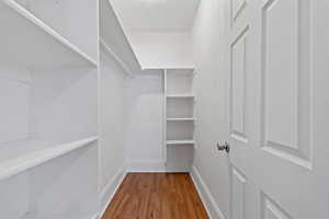 Walk in closet with hardwood / wood-style flooring