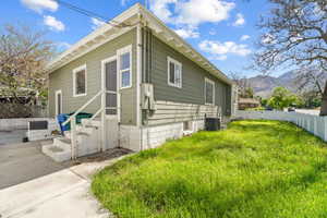 View of side of home with a lawn, a mountain view, and central AC unit