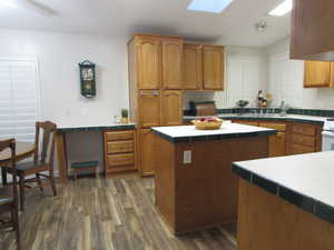 Kitchen with a center island, dark hardwood / wood-style floors, a skylight, and sink