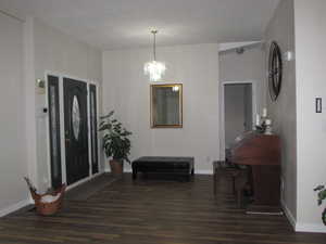 Main entryway featuring leaded glasswork front door, dark hardwood / wood-style flooring and a notable chandelier