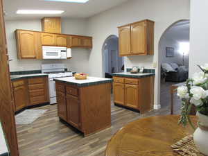 Kitchen with tile edged counters, a center island, dark hardwood / wood-style floors, and white appliances