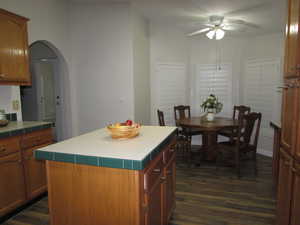 Kitchen & Dining area featuring dark hardwood / wood-style flooring, ceiling fan, and a center island