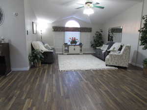 Living room featuring ceiling fan, dark wood-type flooring, and vaulted ceiling