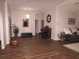 Main entry with lofted ceiling, dark wood-type flooring, and a notable chandelier