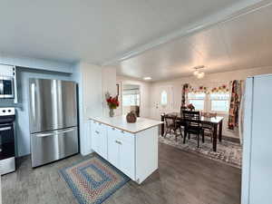 Kitchen with appliances with stainless steel finishes, dark hardwood / wood-style flooring, and white cabinetry