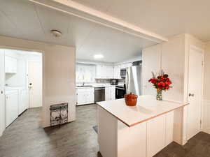 Kitchen featuring a breakfast bar, stainless steel appliances, sink, separate washer and dryer, and white cabinetry