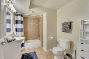 Full bathroom featuring vanity, tile patterned flooring, toilet, a textured ceiling, and shower / tub combo with curtain