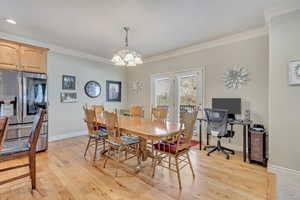 Dining space with crown molding, light hardwood / wood-style floors, and a notable chandelier