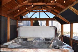 Exterior space featuring a jacuzzi, lofted ceiling with beams, and wood ceiling