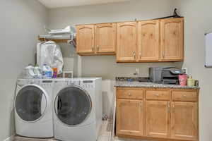 Washroom with cabinets, light tile patterned floors, and washing machine and dryer