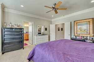 Bedroom featuring connected bathroom, light colored carpet, ceiling fan, and ornamental molding