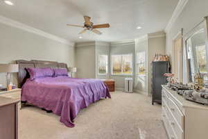 Bedroom featuring ceiling fan, crown molding, and light carpet